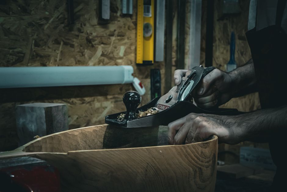 Menuisier lissant une planche de bois avec un rabot à main