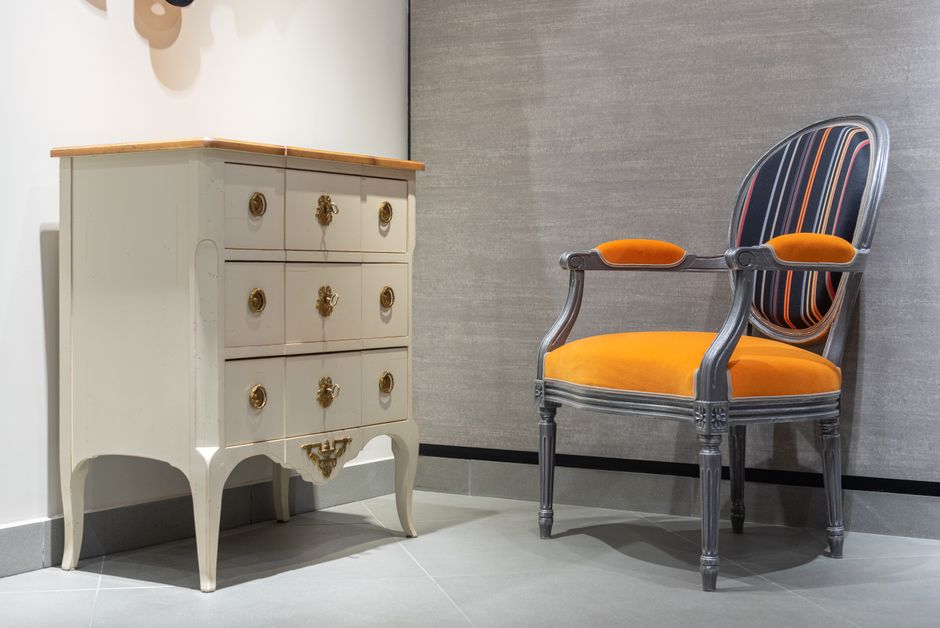 Commode en bois restaurée à côté d'un fauteuil dans un appartement lumineux