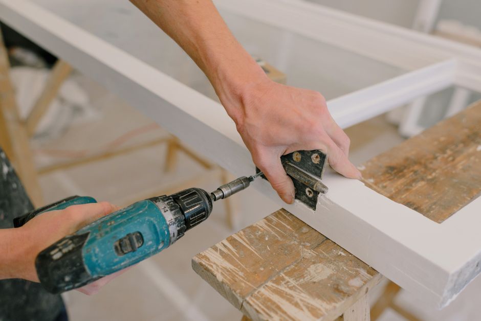 Menuisier posant une charnière sur une menuiserie en bois sur mesure